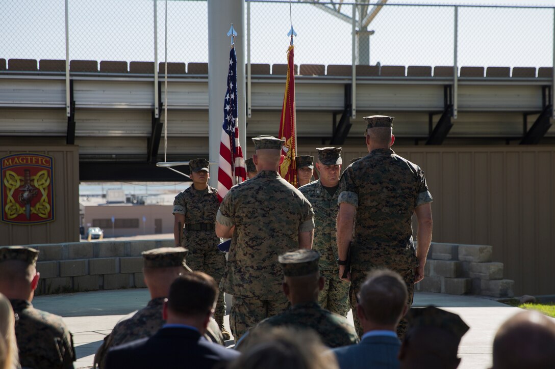 Maj. Gen. William F. Mullen III, commanding general, Marine Corps Air Ground Combat Center, prepares to present Lt. Col. Robert L. Warfield II, director, Marine Corps Community Services, with an award during Warfield’s retirement ceremony at the flag pole aboard the Marine Corps Air Ground Combat Center, Twentynine Palms, Calif., April 27, 2018. Warfield retired after 27 years of honorable service to the Marine Corps. (U.S Marine Corps photo by Lance Cpl. Margaret Gale)