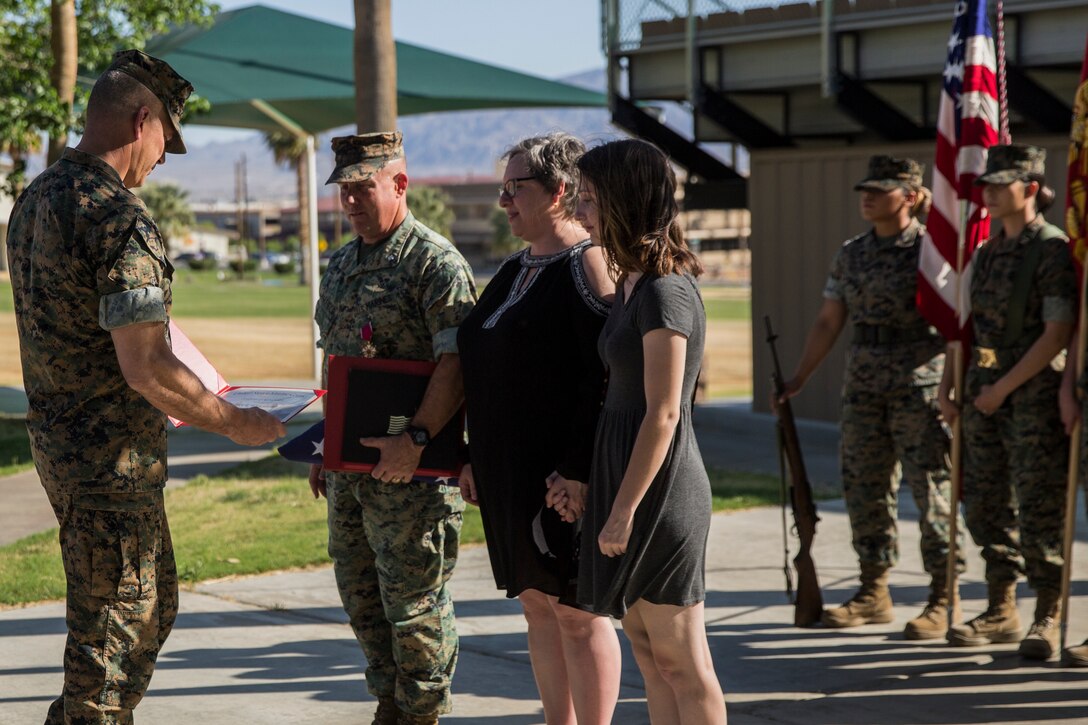 Maj. Gen. William F. Mullen III, commanding general, Marine Corps Air Ground Combat Center, presents Leah Warfield, wife of Lt. Col. Robert L. Warfield II, director, Marine Corps Community Services,  with an award during Warfield’s retirement ceremony  at the flag pole aboard the Marine Corps Air Ground Combat Center, Twentynine Palms, Calif., April 27, 2018. Warfield retired after 27 years of honorable service to the Marine Corps. (U.S Marine Corps photo by Lance Cpl. Margaret Gale)
