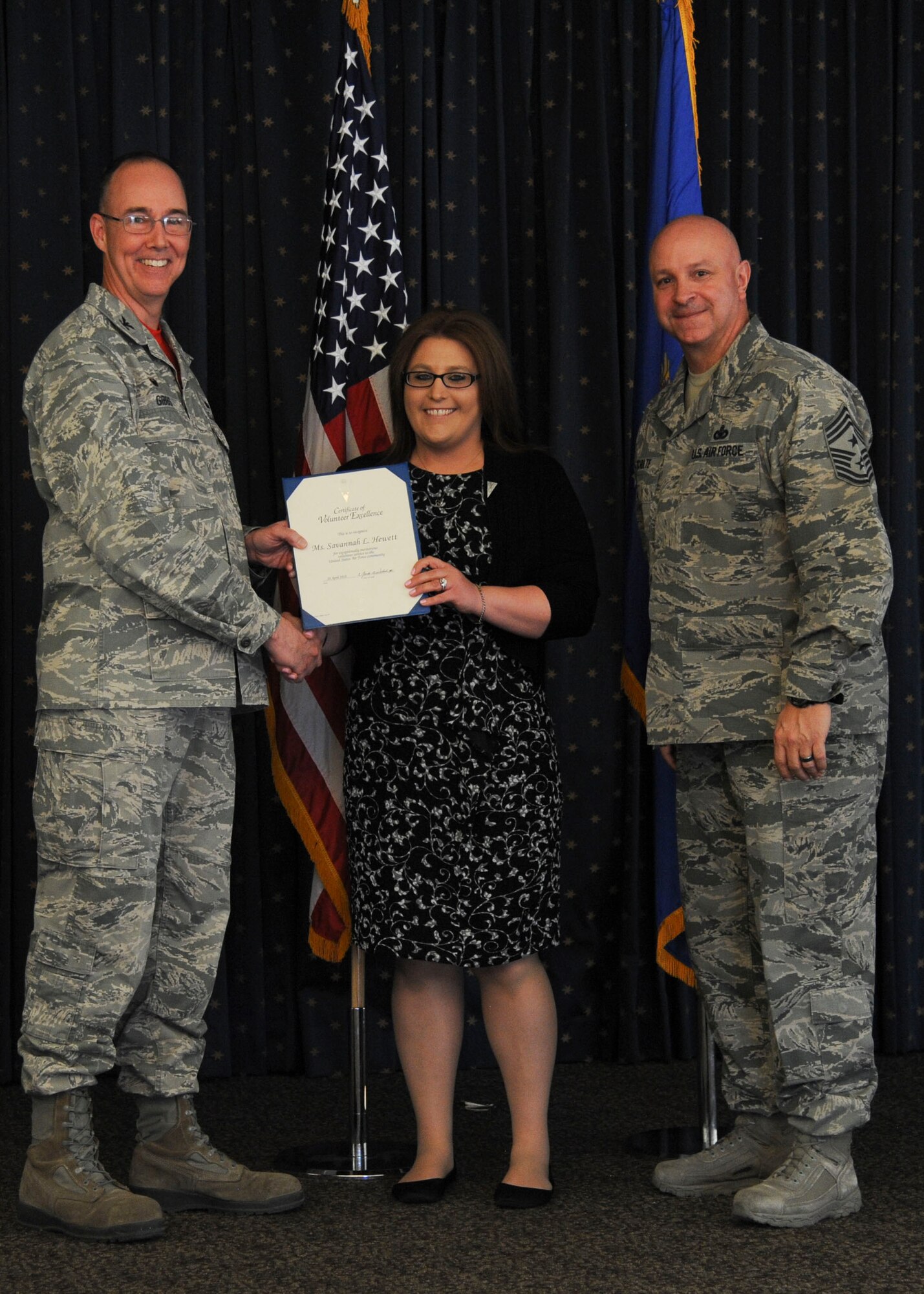 Savannah Hewett, 377th Security Forces Group Key Spouse, is presented with her award for Volunteer of the Year 2017 at the Volunteer Recognition Ceremony April 20 at the Mountain View Club as 377th Air Base Wing Commander Col. Richard Gibbs (left) and Command Chief Master Sgt. Chad Schulte (right) congratulate her.