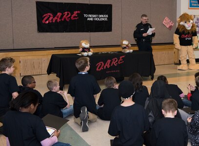 Michael J. Crerend, lead police officer with the 673d Security Forces Squadron and Drug Abuse Resistance Education officer, reads to the students from the D.A.R.E. program at Ursa Major Elementary School at Joint Base Elmendorf-Richardson, Alaska, May 2, 2018. D.A.R.E. is a program designed to provide students with the knowledge and tools they need to resist drugs, alcohol and other high-risk behaviors.