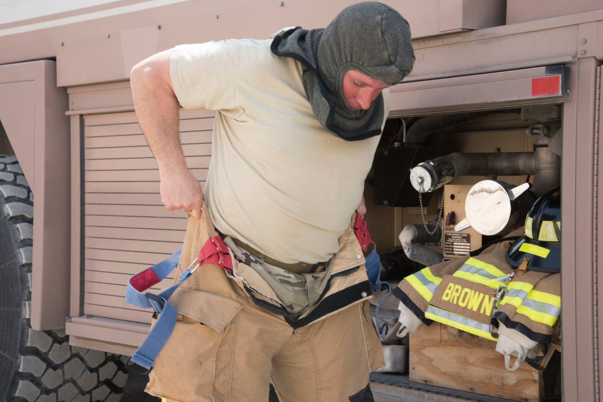 A fire fighter from the 380th Expeditionary Civil Engineer Squadron puts on his fire equipment during a joint agency exercise here, May 2. (U.S. Air National Guard photo by Staff Sgt. Erica Rodriguez)