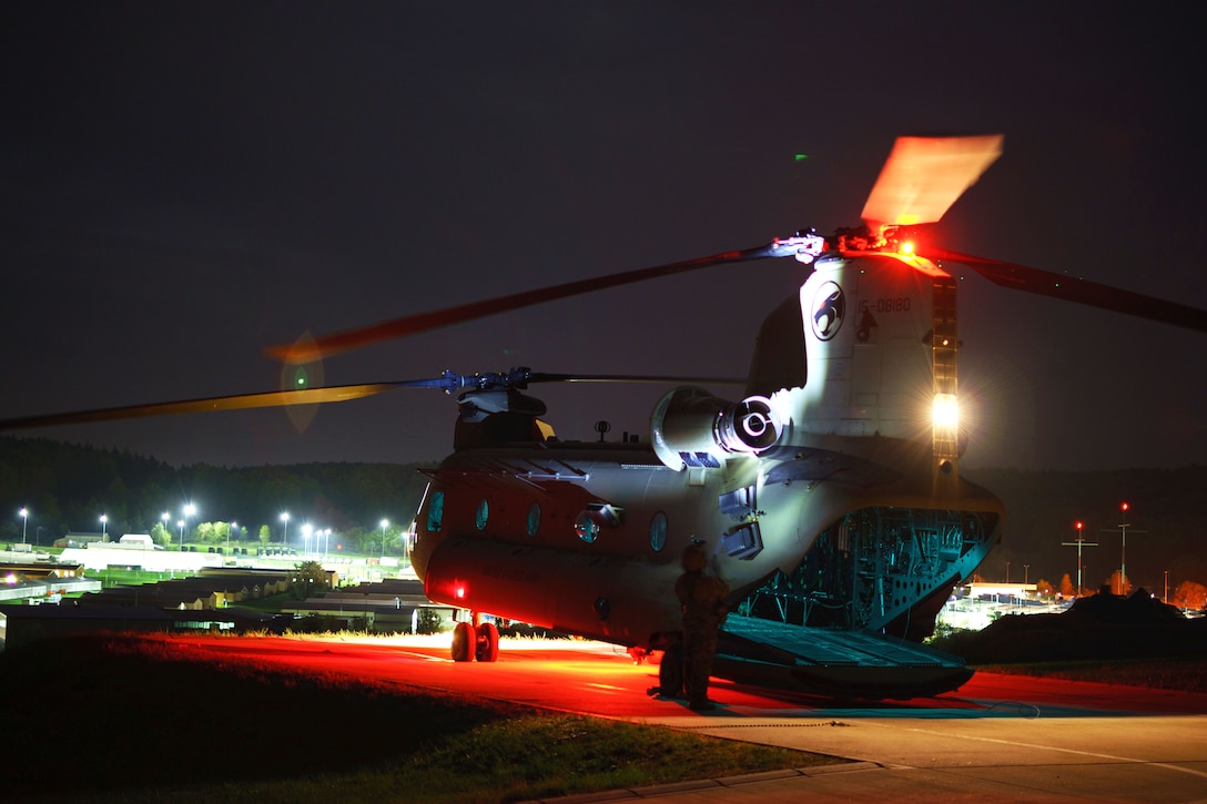 A soldier shines a light on the tail of a CH-47 Chinook helicopter.