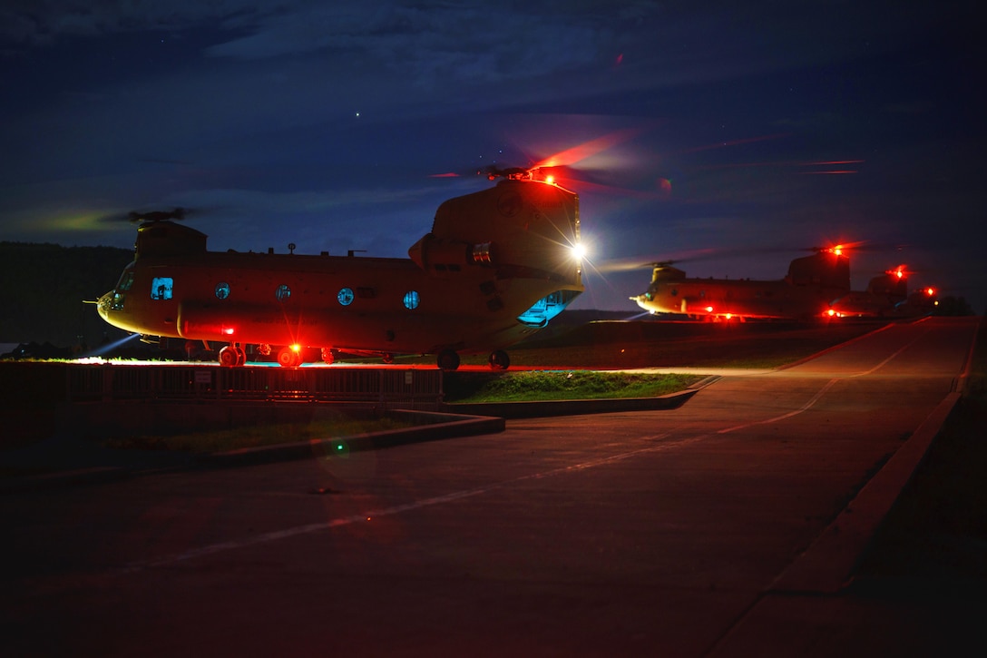 Army pilots and crew chiefs prepare their Chinook helicopters for takeoff.