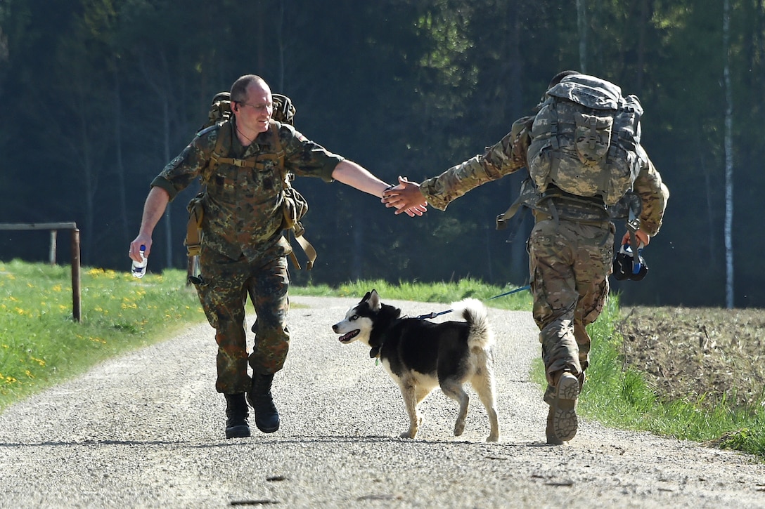 A German and U.S. soldier clap hands during a ruck march.