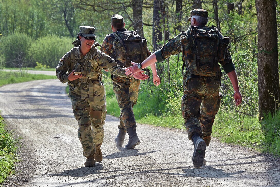 A U.S. and German soldier claps hands during a ruck march.