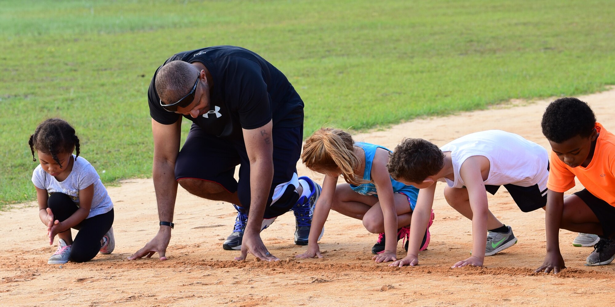 U.S. Air Force Senior Master Sgt. Antonio Mack, 325th Fighter Wing Air Forces Northern/Tyndall Command Center and 325th Fighter Wing Staff Agency superintendent, displays proper starting form to his younger athletes at Rutherford High School in Panama City, Fla., April 24, 2018. Mack coaches children from Tyndall Air Force Base and the surrounding community for track and field competitions. (U.S. Air Force photo by Senior Airman Cody R. Miller/Released)