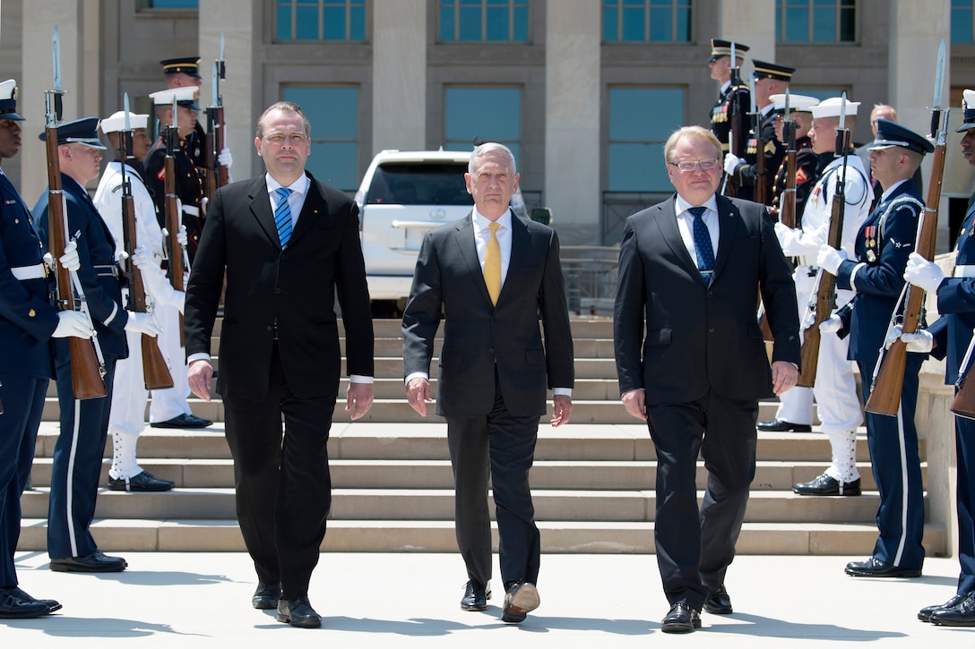 Defense Secretary James N. Mattis walks between his Finnish and Swedish counterparts while flanked by troops outside the Pentagon.