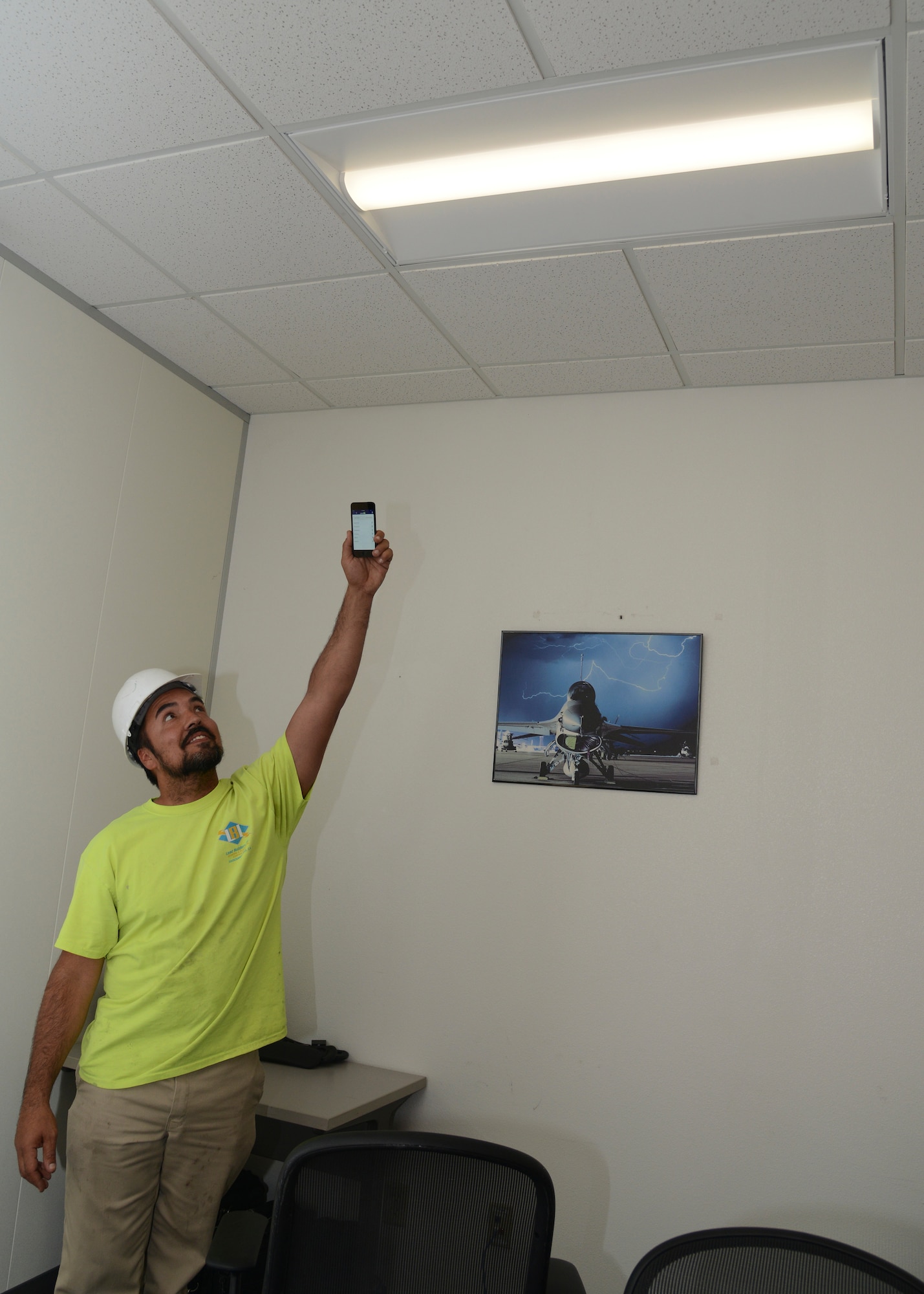 Luis Sandoval, Lead Builders electrical foreman, demonstrates how to adjust a new light fixture with a downloadable app for a smart device. The 412th Civil Engineer Group is overseeing a large lighting upgrade across Edwards AFB that will bring better working conditions and savings to the base. (U.S. Air Force photo by Kenji Thuloweit)