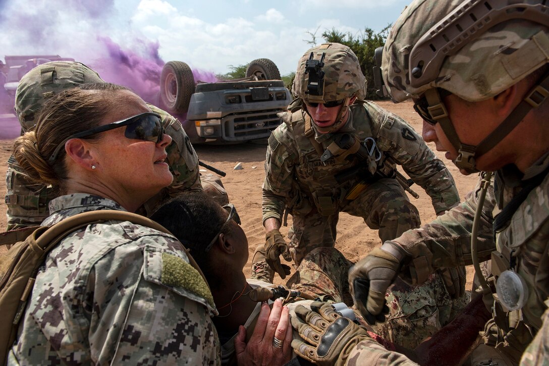 Soldiers provide medical aid to a role-playing patient during mass casualty training exercise.
