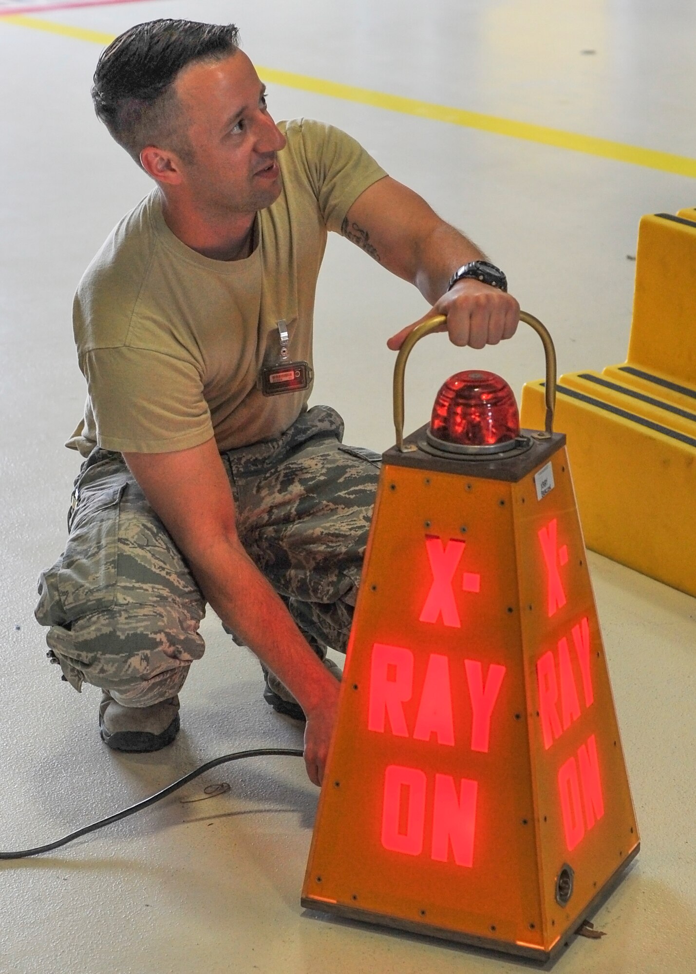 Tech. Sgt. Clayton Wilson, a nondestructive inspection journeyman with the 910th Maintenance Squadron, plugs in an “X-Ray On” warning sign May 2 in hangar 302 at Youngstown Air Reserve Station before X-raying the structural supports of a C-130H Hercules.