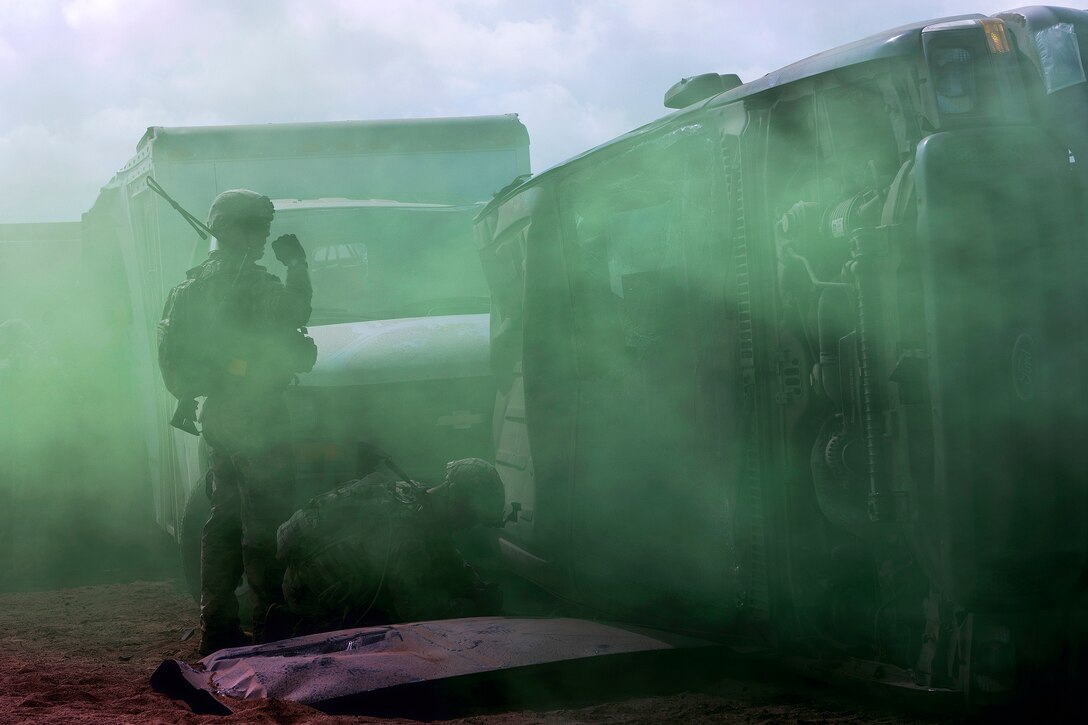 Airmen attempt to access an overturned vehicle to rescue a simulated casualty.