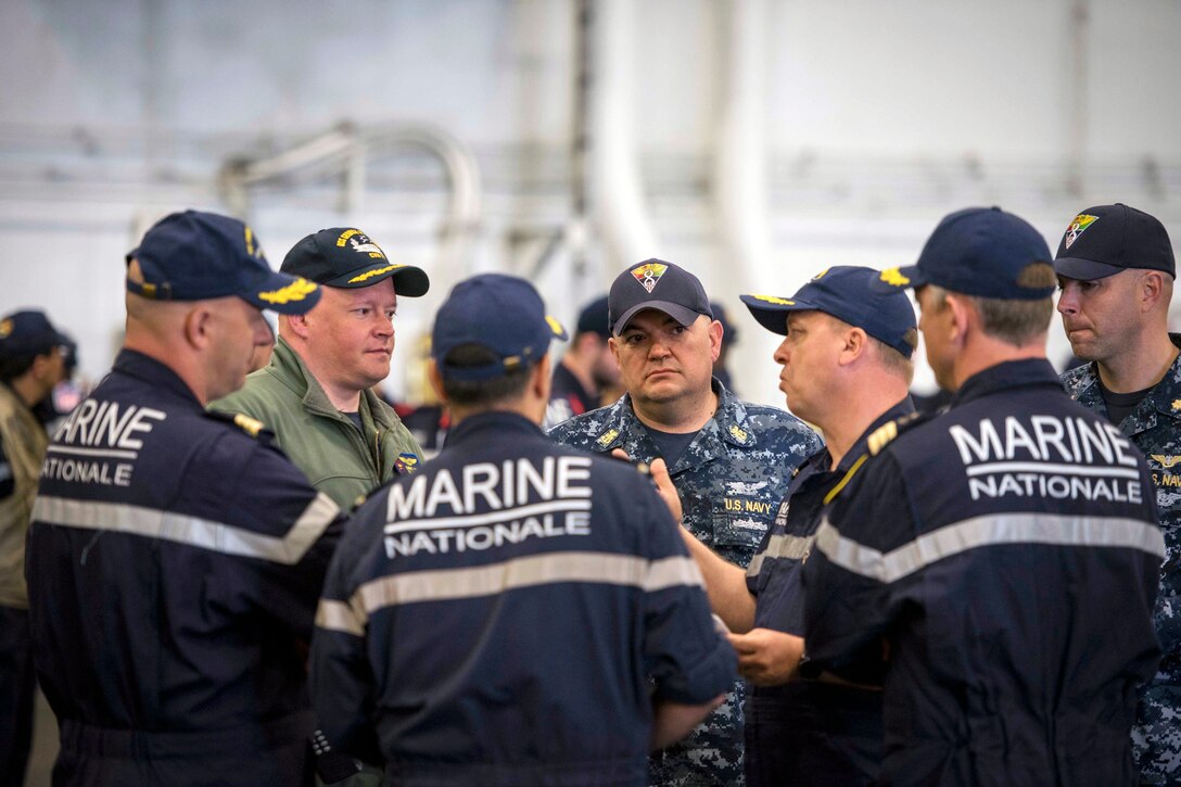 A Navy officer speaks with French sailors.