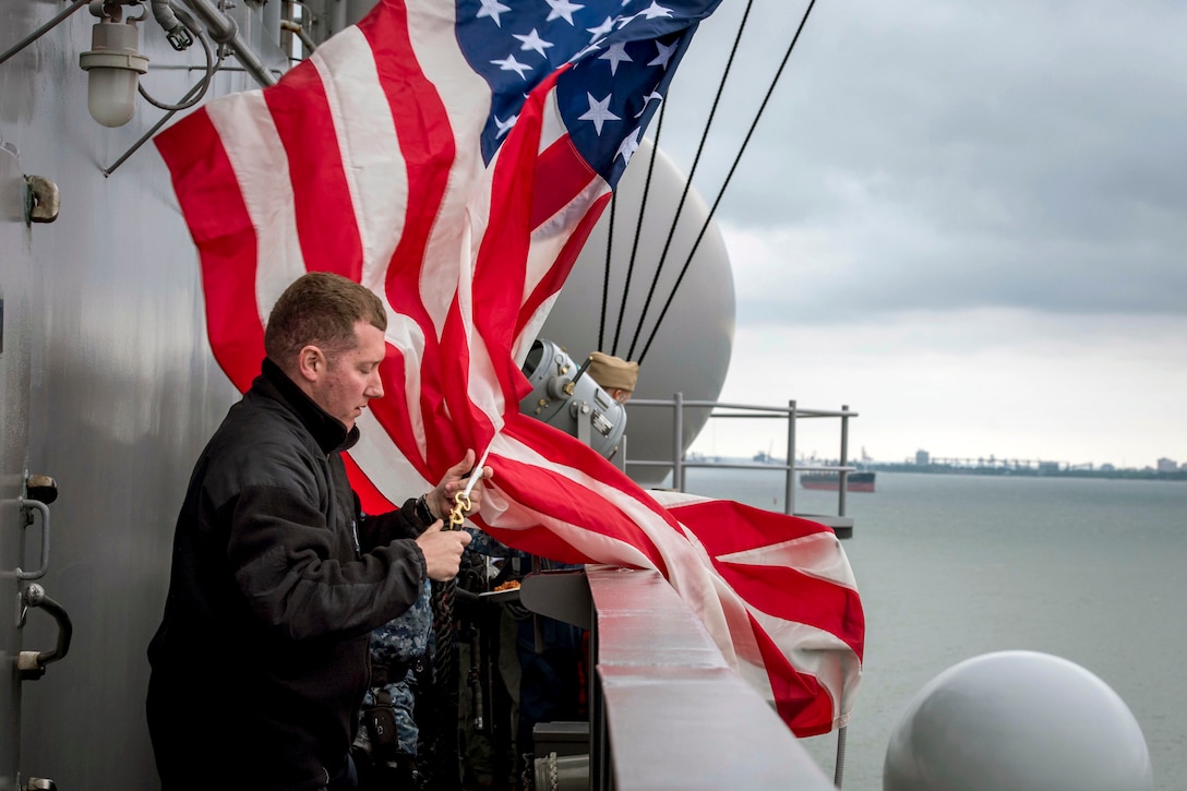 A sailor prepares to hoist the U.S. flag at sea aboard the aircraft carrier USS George H.W. Bush.