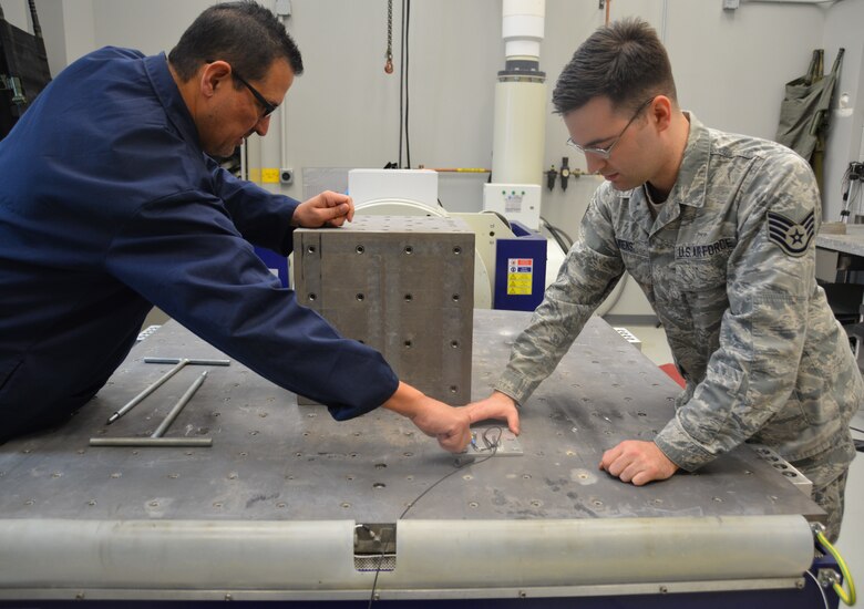 David Ryerse and Staff Sgt. Taylor Wiens mount a sensor designed to measure acceleration on the Aeromedical Laboratory's multi-axis table ("shake table"). (U.S. Air Force photo by Gina M. Giardina)