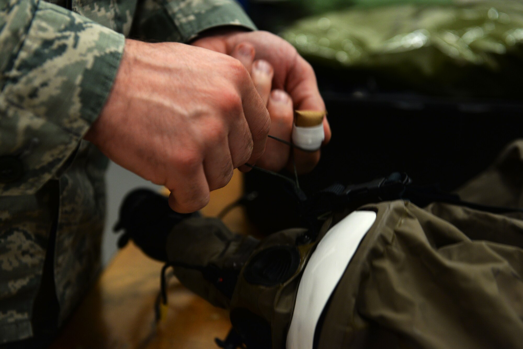 A U.S. Airman from the 100th Operations Support Squadron aircrew flight equipment shop tacks an oxygen mask to secure the threading of a mask lining at RAF Mildenhall, England, April 24, 2018. The AFE shop is the insurance of the aircrew and keeps emergency kits prepared in case of an in-flight emergency. (U.S. Air Force photo by Airman 1st Class Alexandria Lee)