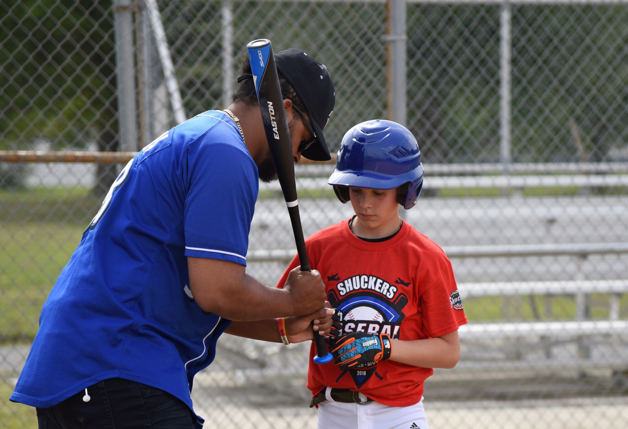 Angel Ventura, Biloxi Shuckers pitcher, assists Maddox Cloutier, son of U.S. Air Force Master Sgt. Brian Cloutier, 558th Flying Training Squadron remotely piloted aircraft pilot training student, Joint Base San Antonio-Randolph Air Force Base, Texas, with batting techniques during the Biloxi Shuckers Youth Baseball Clinic on the youth center baseball field at Keesler Air Force Base, Mississippi, May 5, 2018. The clinic provided hitting, pitching, base running and fielding instruction from members of the Biloxi Shuckers minor league baseball team. (U.S. Air Force photo by Kemberly Groue)