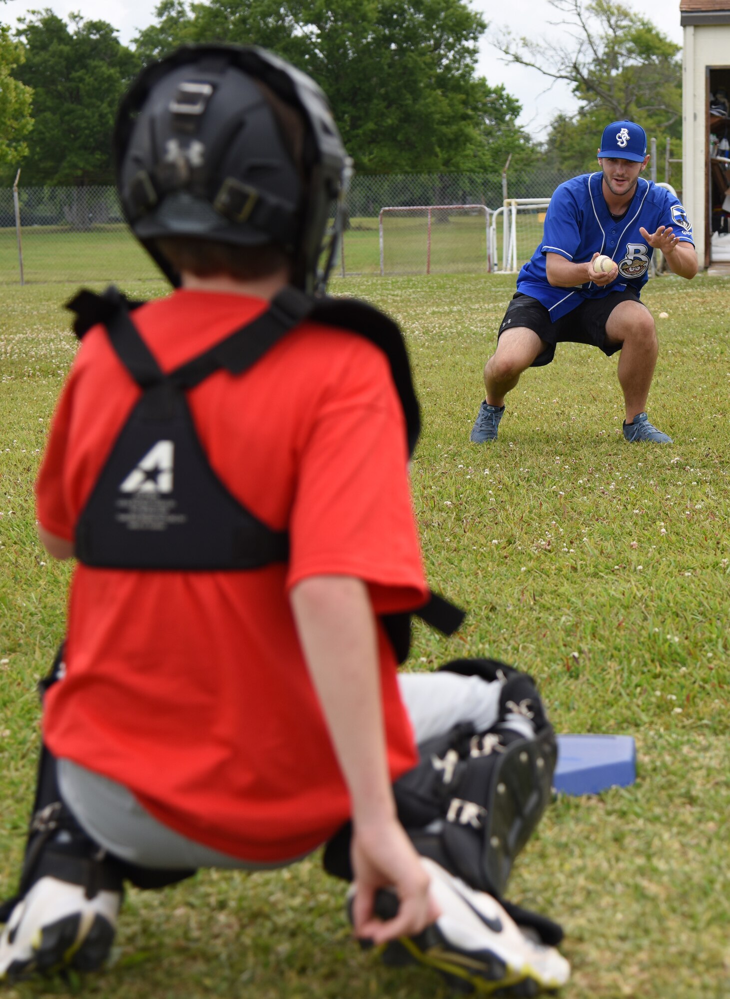 Thomas Jankins, Biloxi Shuckers pitcher, provides catching techniques to Tristan Fisher, son of U.S. Air Force Chief Master Sgt. Anthony Fisher, 81st Training Group superintendent, during the Biloxi Shuckers Youth Baseball Clinic on the youth center baseball field at Keesler Air Force Base, Mississippi, May 5, 2018. The clinic provided hitting, pitching, base running and fielding instruction from members of the Biloxi Shuckers minor league baseball team. (U.S. Air Force photo by Kemberly Groue)