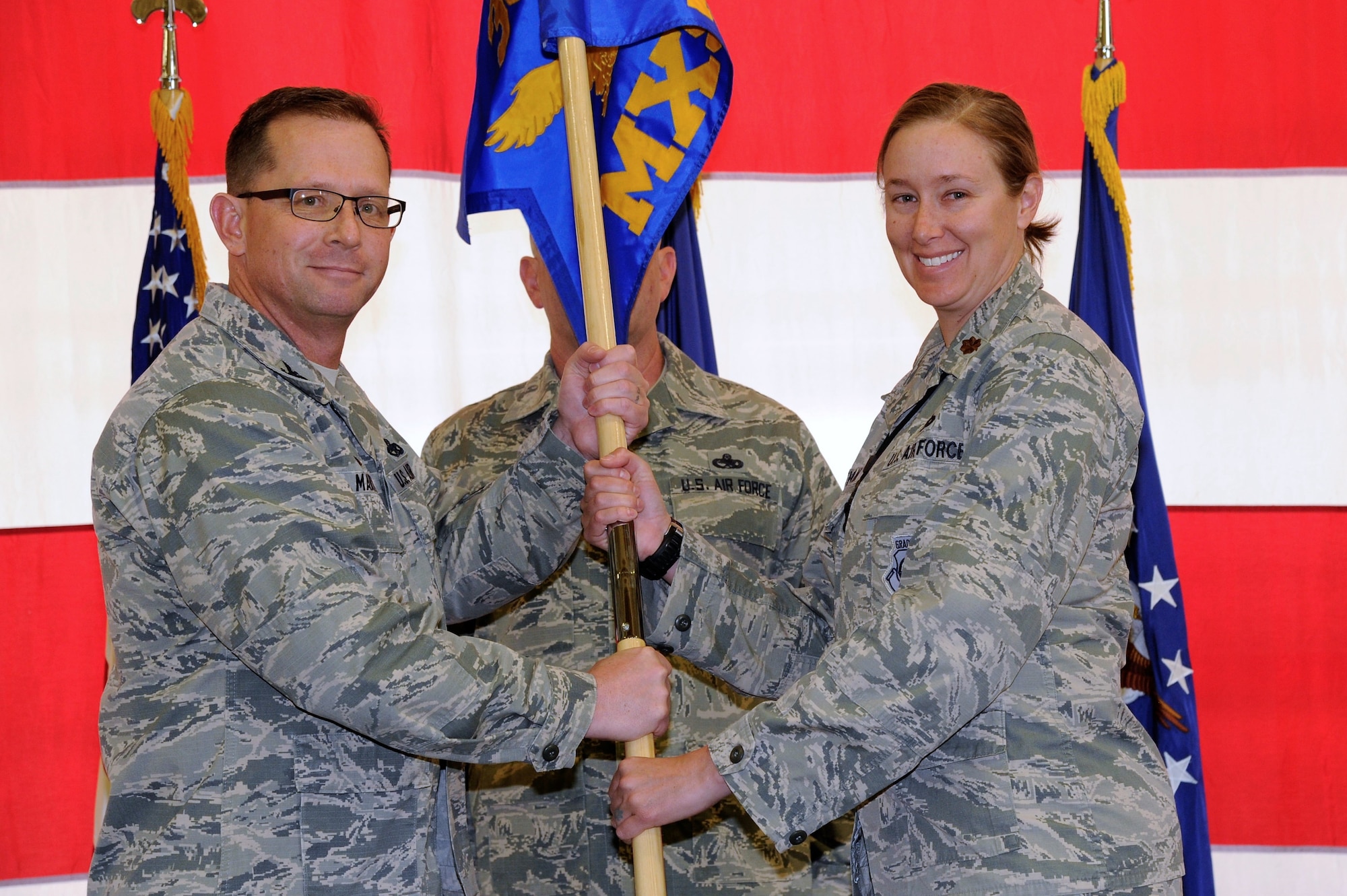 Col. Jason Martin, the 302nd Maintenance Group commander, passes the 302nd Maintenance Squadron guidon to Maj. Katherine Schifani, the new 302nd MXS commander, during an assumption of command ceremony at Peterson Air Force Base, Colorado, May 5, 2018.