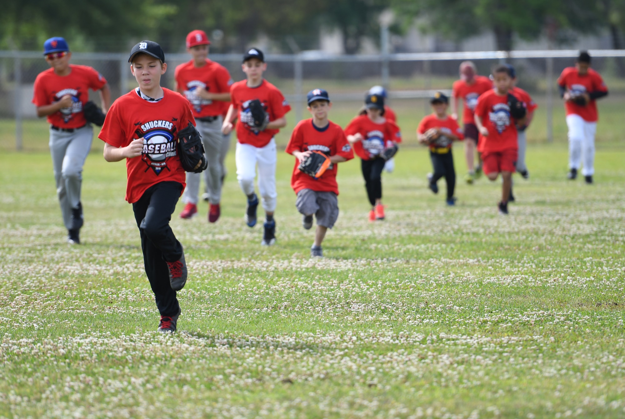 Keesler children run warm-up laps during the Biloxi Shuckers Youth Baseball Clinic on the youth center baseball field at Keesler Air Force Base, Mississippi, May 5, 2018. More than 20 children attended the clinic that provided hitting, pitching, base running and fielding instruction from members of the Biloxi Shuckers minor league baseball team. (U.S. Air Force photo by Kemberly Groue)