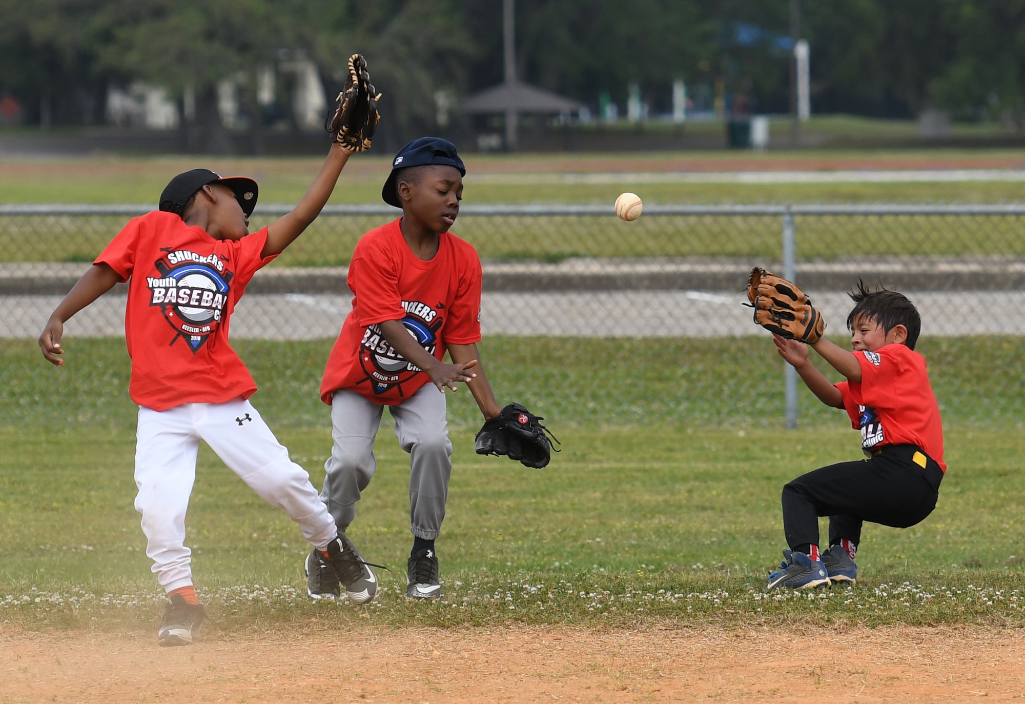 Keesler children try to catch the ball during the Biloxi Shuckers Youth Baseball Clinic on the youth center baseball field at Keesler Air Force Base, Mississippi, May 5, 2018. More than 20 children attended the clinic that provided hitting, pitching, base running and fielding instruction from members of the Biloxi Shuckers minor league baseball team. (U.S. Air Force photo by Kemberly Groue)