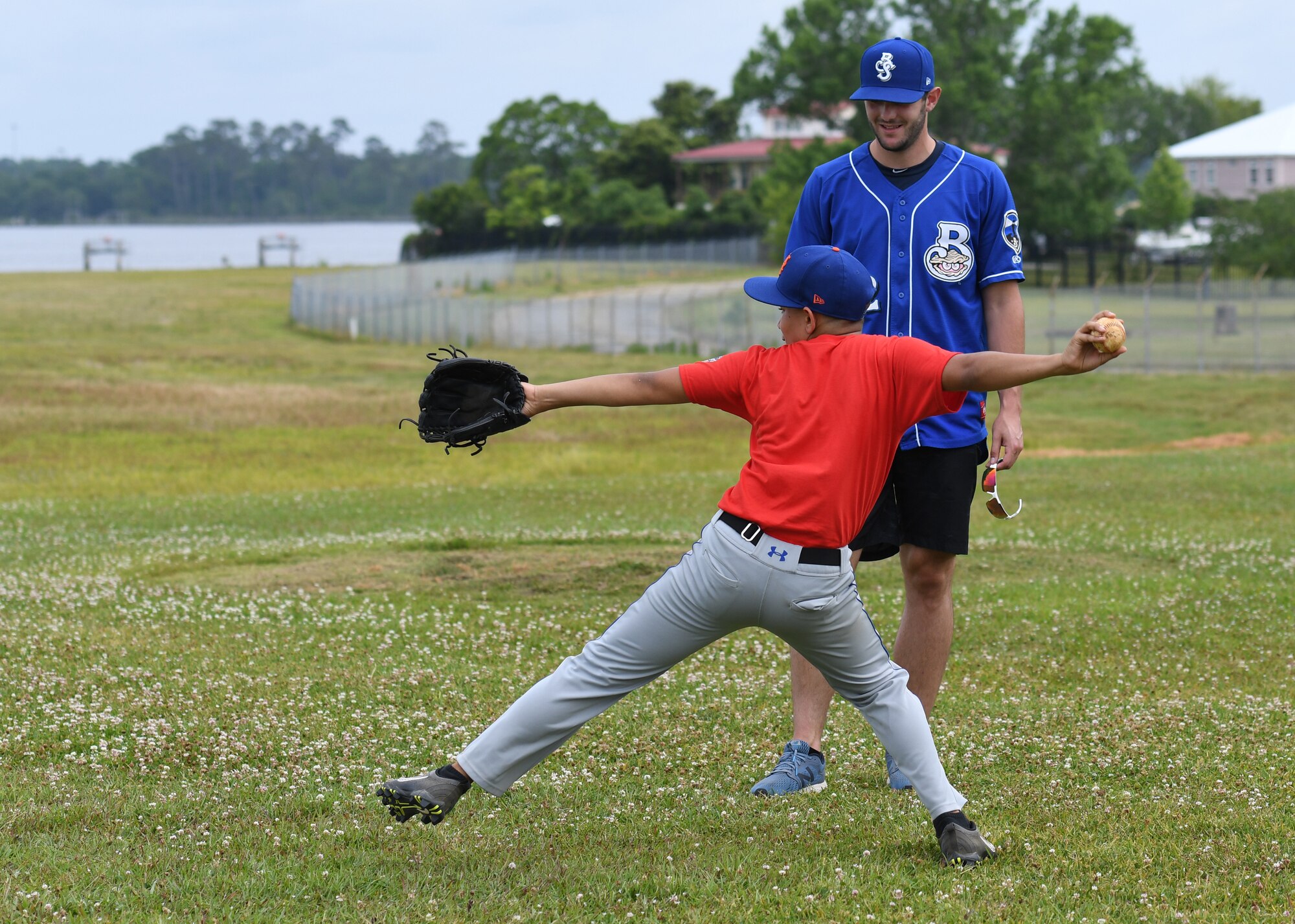 Dylan Moore, Biloxi Shuckers shortstop, assists Andre Torres, son of Andre Torres, 81st Medical Support Squadron defense medical logistics standard support clerk, with pitching techniques during the Biloxi Shuckers Youth Baseball Clinic  on the youth center baseball field at Keesler Air Force Base, Mississippi, May 5, 2018. More than 20 children attended the clinic that provided hitting, pitching, base running and fielding instruction from members of the Biloxi Shuckers minor league baseball team.  (U.S. Air Force photo by Kemberly Groue)