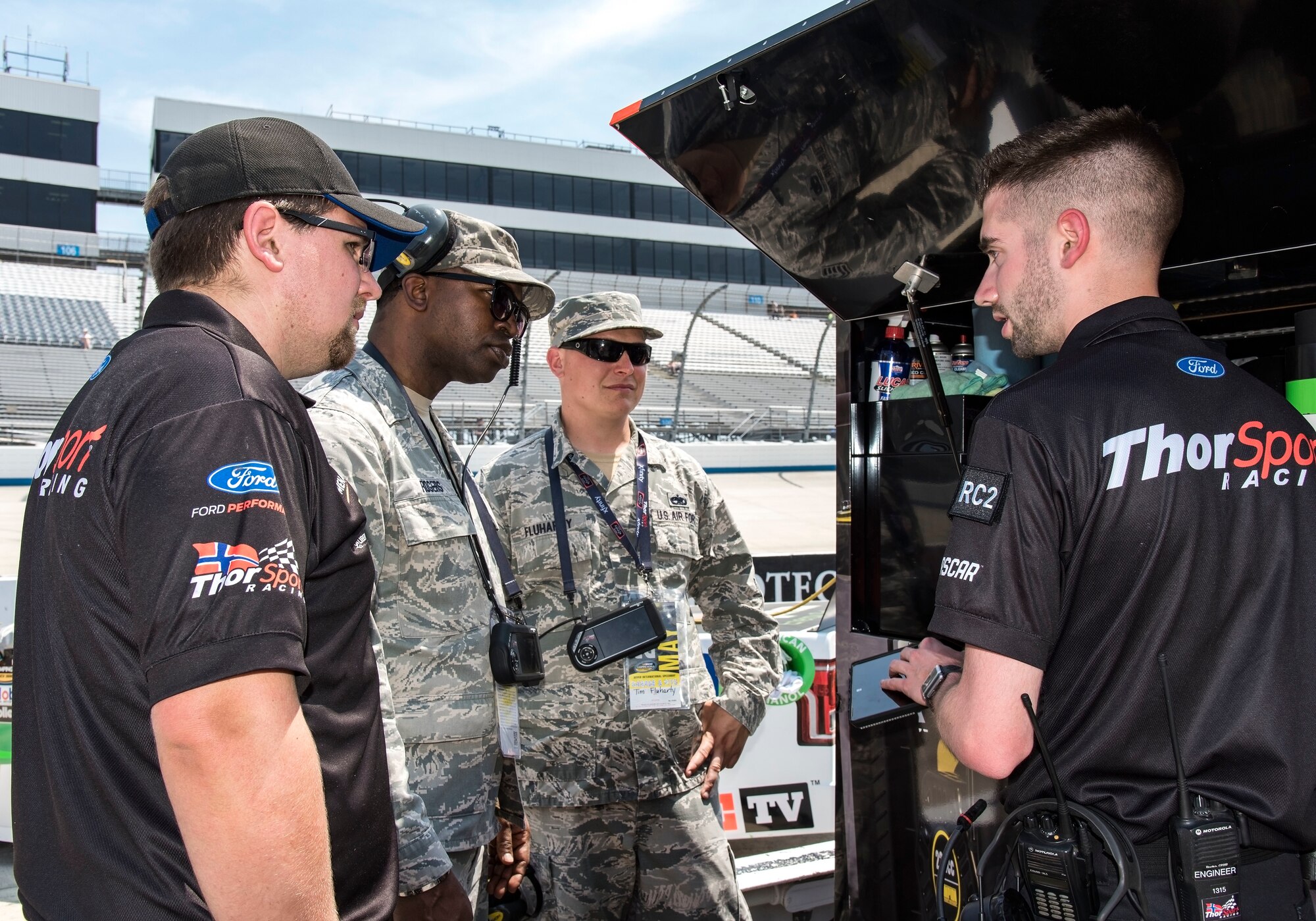 Tech. Sgt. Mikel Rogers, center left, 436th Civil Engineer Squadron emergency management operations NCO in charge, and Tech. Sgt. Timothy Fluharty, center right, 373rd Training Squadron, Detachment 3, C-5M hydraulics instructor, speak with ThorSport Racing team members Nick Gardiner and Brian Ross, mechanic and race engineer, respectively, May 4, 2018, at Dover International Speedway, Dover, Del. Honorary pit crew members spoke with team members on pit road prior to qualifying for the 19th Annual “JEGS 200” race later that afternoon. (U.S. Air Force photo by Roland Balik)