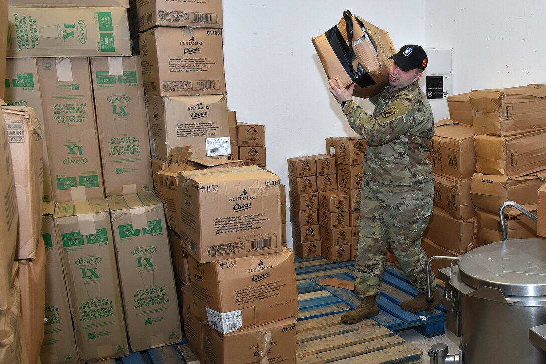 A soldier moves boxes of supplies.