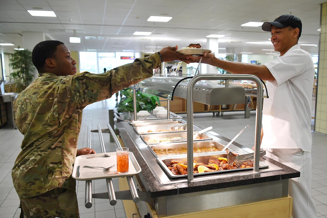 A culinary specialist serves a meal to a soldier.