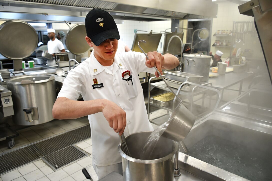 A culinary specialist pours water into a kettle.
