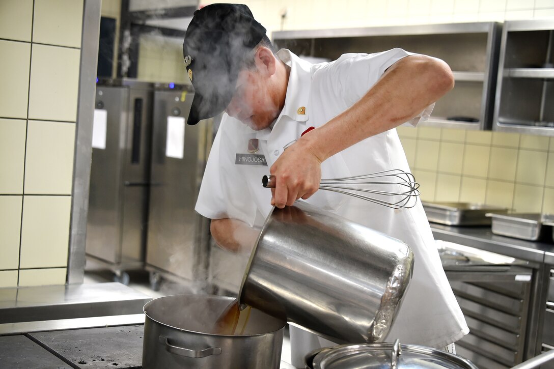A culinary specialist pours beef broth into a kettle.