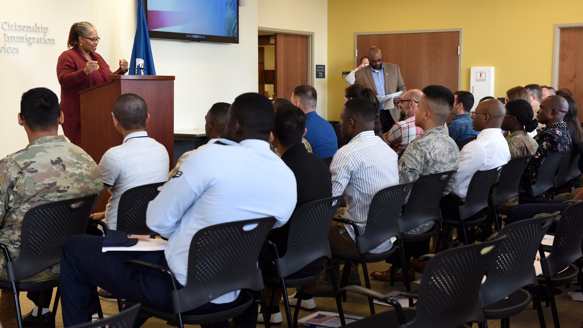 Service members in a court room wait for naturalization.