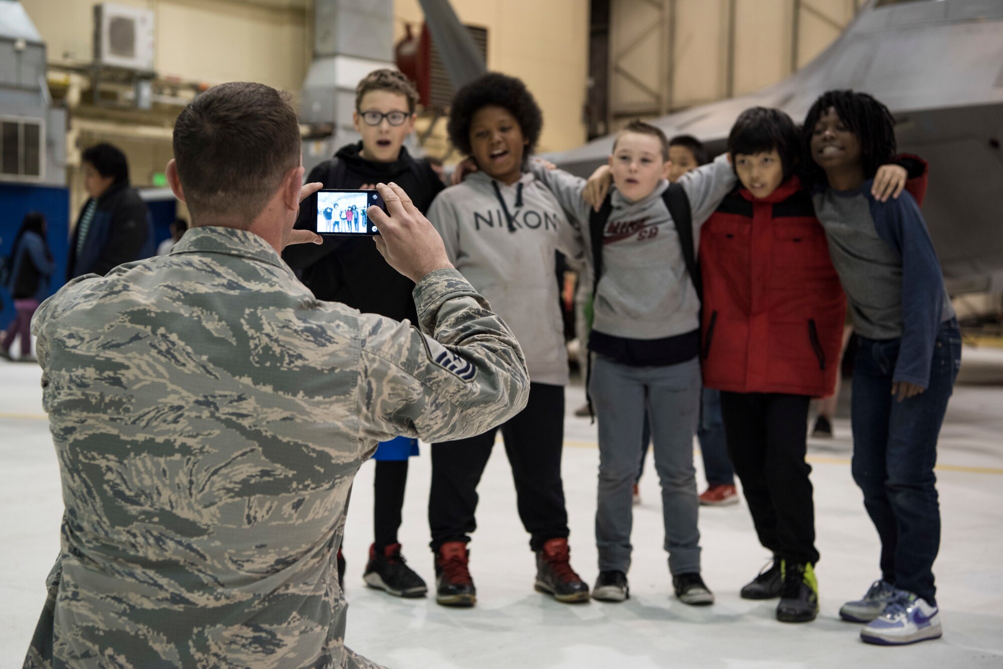 Air Force Master Sgt. Jamie Walker, 3rd Maintenance Squadron assistant first sergeant, takes a photo of several 5th-grade students from Wonder Park and Mountain View elementary schools at the “Day in the Life of Airmen” tour on Joint Base Elmendorf-Richardson, Alaska, May 4, 2018. The tour provided an interactive educational experience for the students while allowing service members the opportunity to serve the local community.
