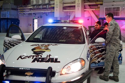 Senior Airman Brandon Moore, 673d Security Forces Squadron installation entry controller, looks on as several 5th-grade students from Wonder Park and Mountain View elementary schools sit in a patrol car at the “Day in the Life of Airmen” tour on Joint Base Elmendorf-Richardson, Alaska, May 4, 2018. The goal of the tour was to provide background knowledge about the work and to entice questions, while giving the students a beyond-the-scenes experience.