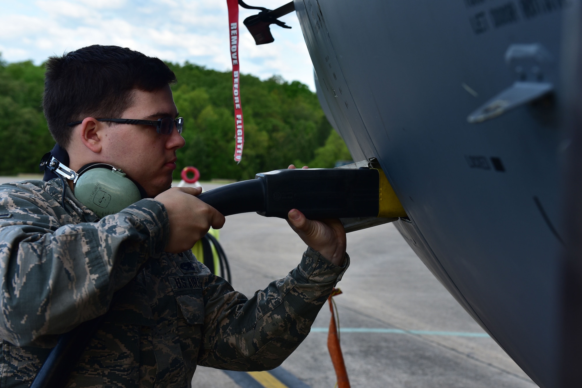 A man puts a large plug into the side of a C-130J.