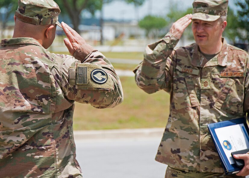 Chief Master Sgt. James Loper, 10th Air Force Command Chief, salutes Lt. Col. Christopher Johnson, 919th Special Operations Communications Squadron commander