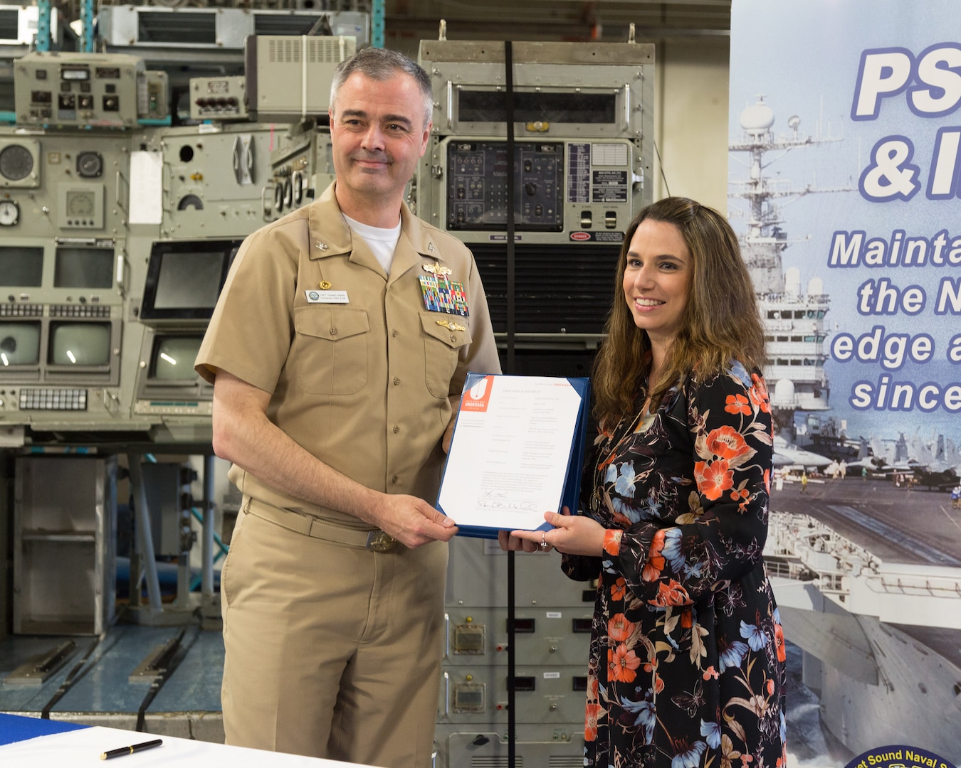 Captain Howard Markle, commander of Puget Sound Naval Shipyard & Intermediate Maintenance Facility, and U.S. Naval Undersea Museum Director Lindy Dosher officially transfer ownership of the control room from the experimental nuclear research submarine NR-1 from the shipyard to the museum during a ceremony in the museum’s private storage area May 8, 2018, in Keyport, Washington. (Photo by Carie Hagins, PSNS & IMF photographer)