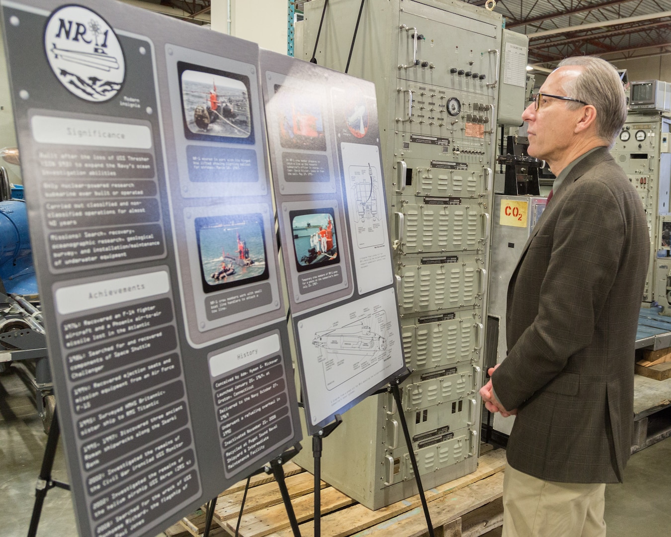 Puget Sound Naval Shipyard & Intermediate Maintenance Facility Executive Director Rick Tift looks at graphics donated by PSNS & IMF that illustrate the size and location of the control room in relation to NR-1. The graphics were produced by Eugene Hernandez, PSNS & IMF illustrator. (Photo by Carie Hagins, PSNS & IMF photographer)