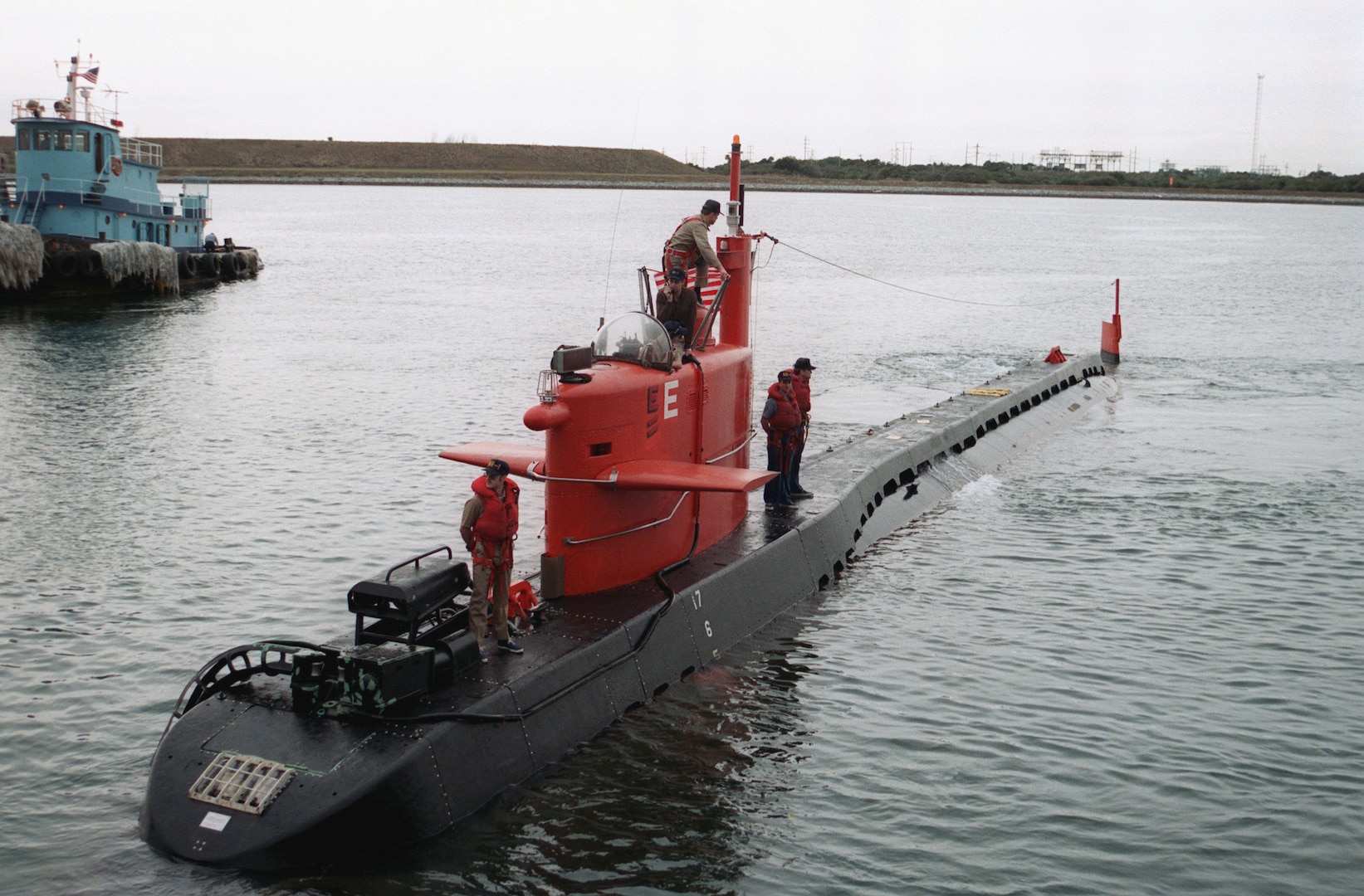 A port bow view of the nuclear-powered research submersible NR-1 as it approaches port in this undated photo. The Sailors atop the mini nuclear submarine illstrate just how small the vessel was. (U.S. Navy photo by JOC Peter D. Sundberg)