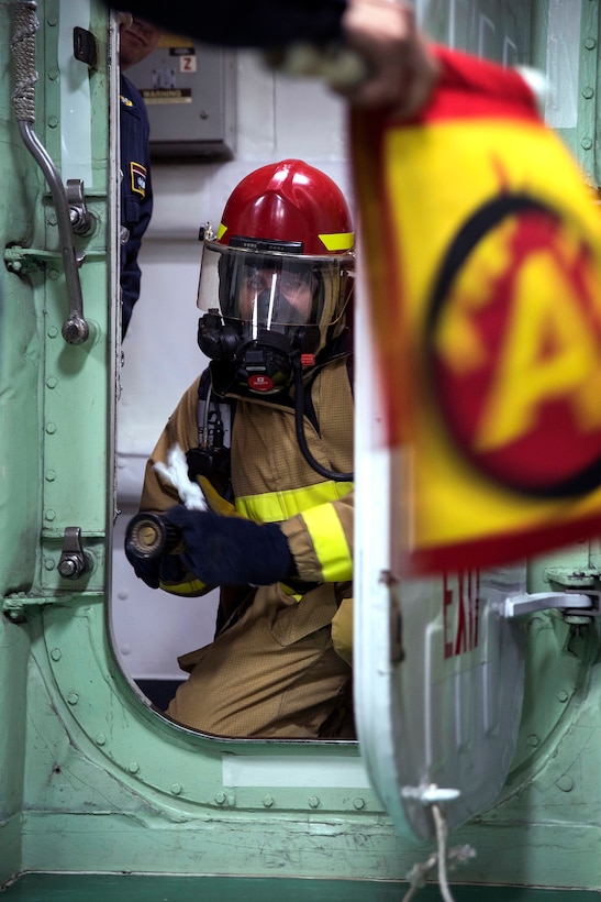 A sailor combats a simulated Class A fire.