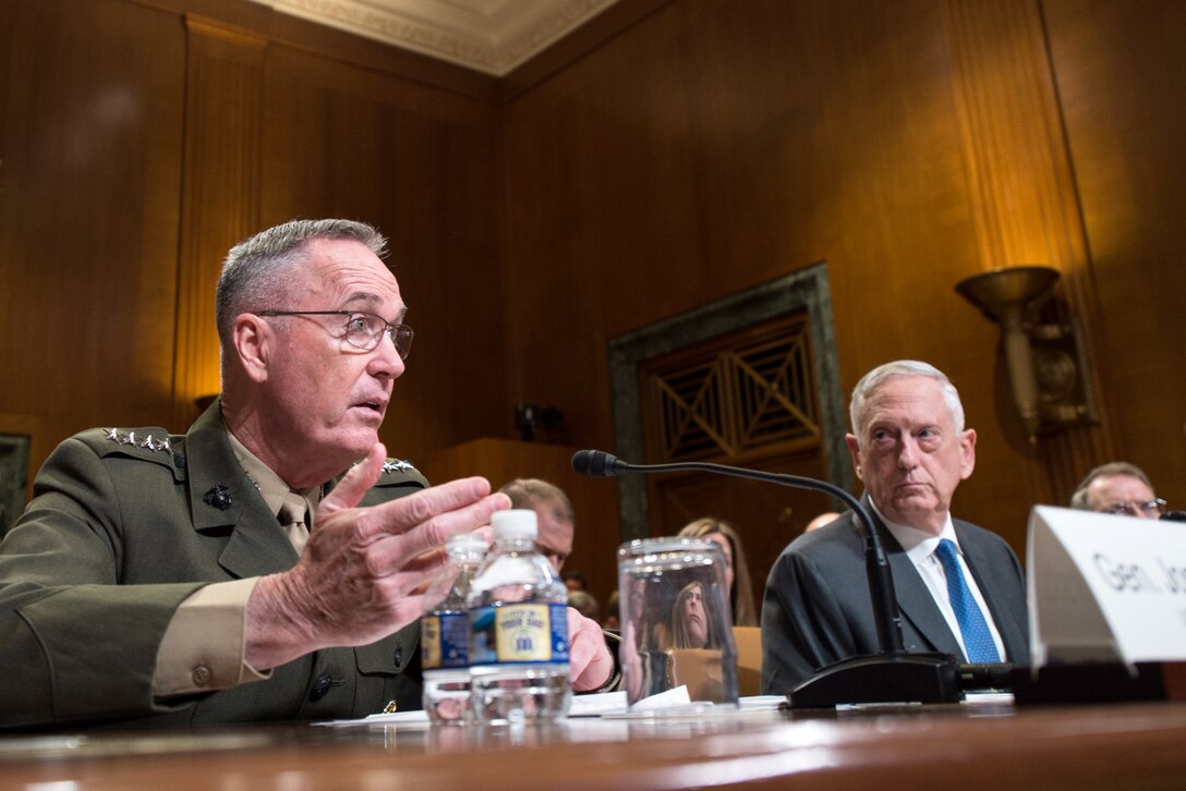 The chairman of the Joint Chiefs of Staff and Defense Secretary James N. Mattis sit behind a desk.