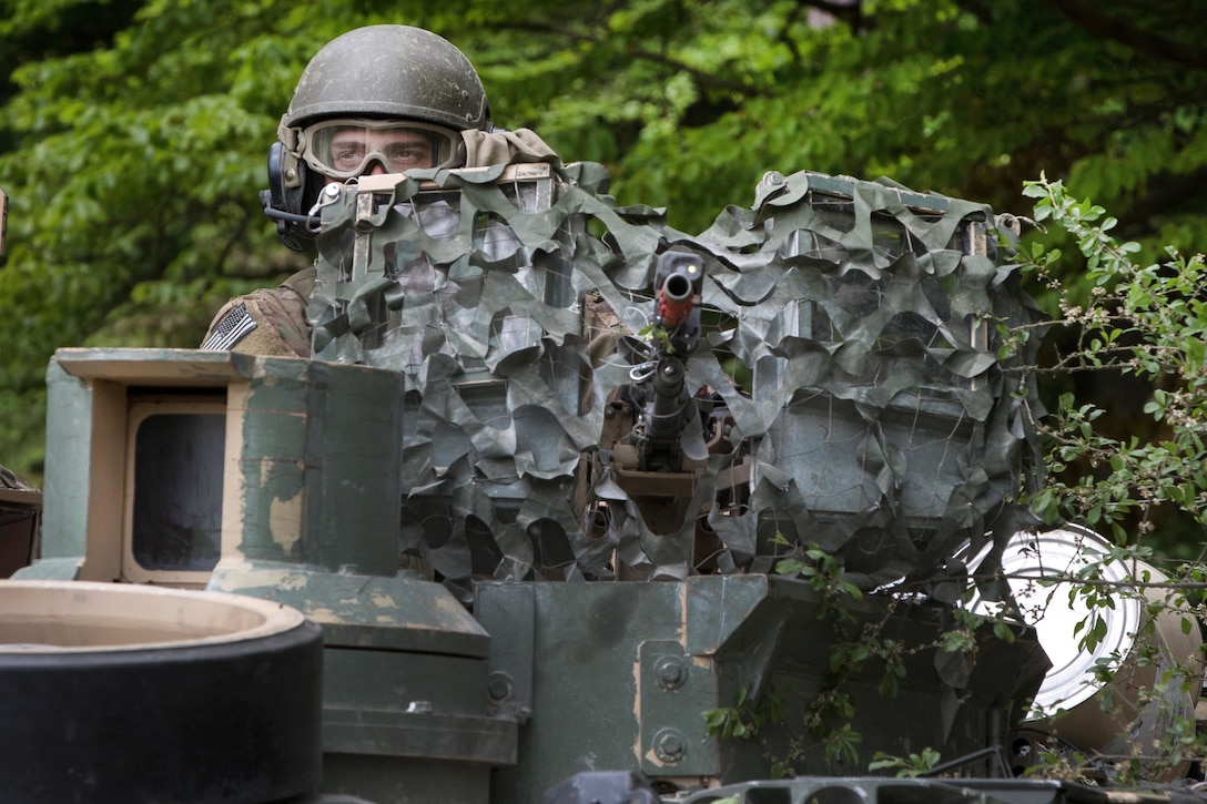 A soldier mans a machine gun atop an M1A1 Abrams tank.