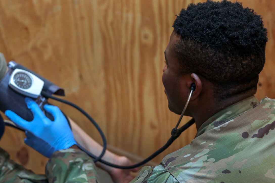 A soldier checks a patient’s blood pressure.