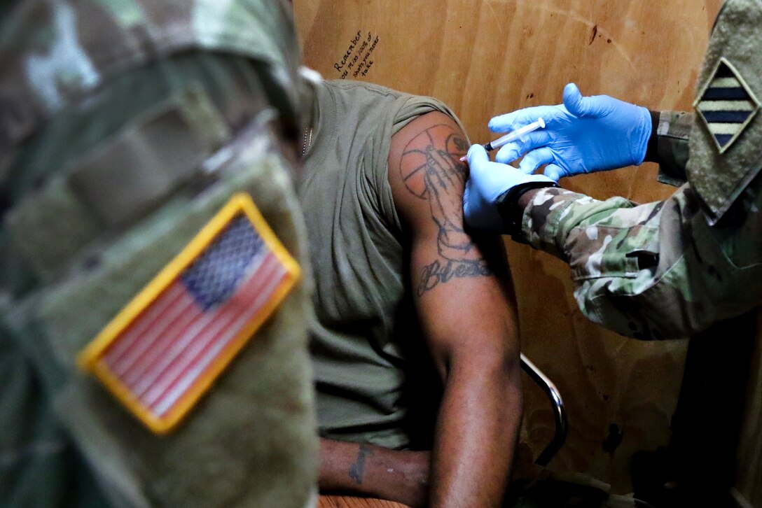 A soldier uses a hypodermic needle and syringe to inject medication.
