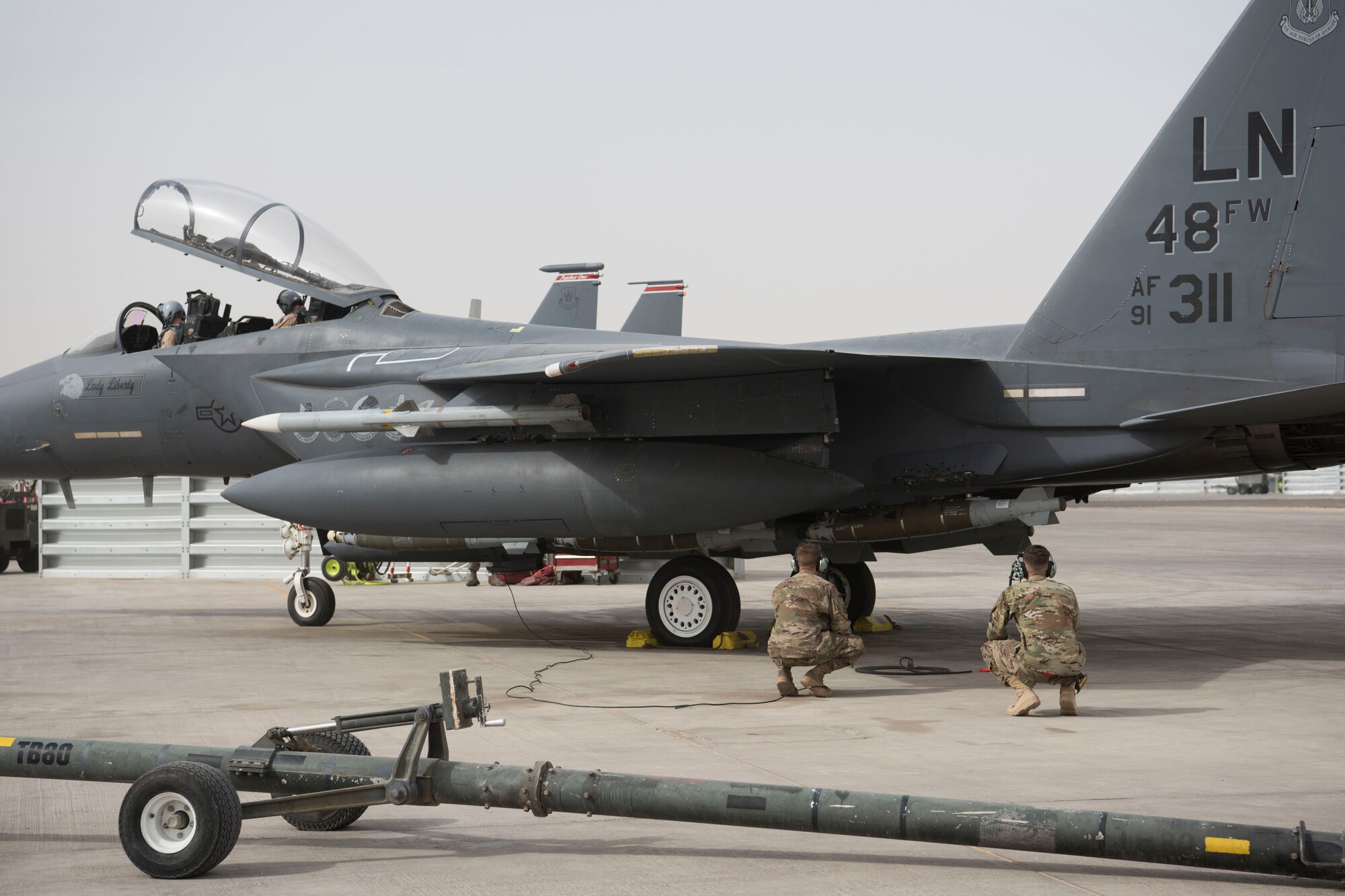 Two Airmen with the 332nd Expeditionary Maintenance Squadron observes the engine of an F-15E Strike Eagle as they perform pre-flight checks May 7, 2018, at an undisclosed location in Southwest Asia.