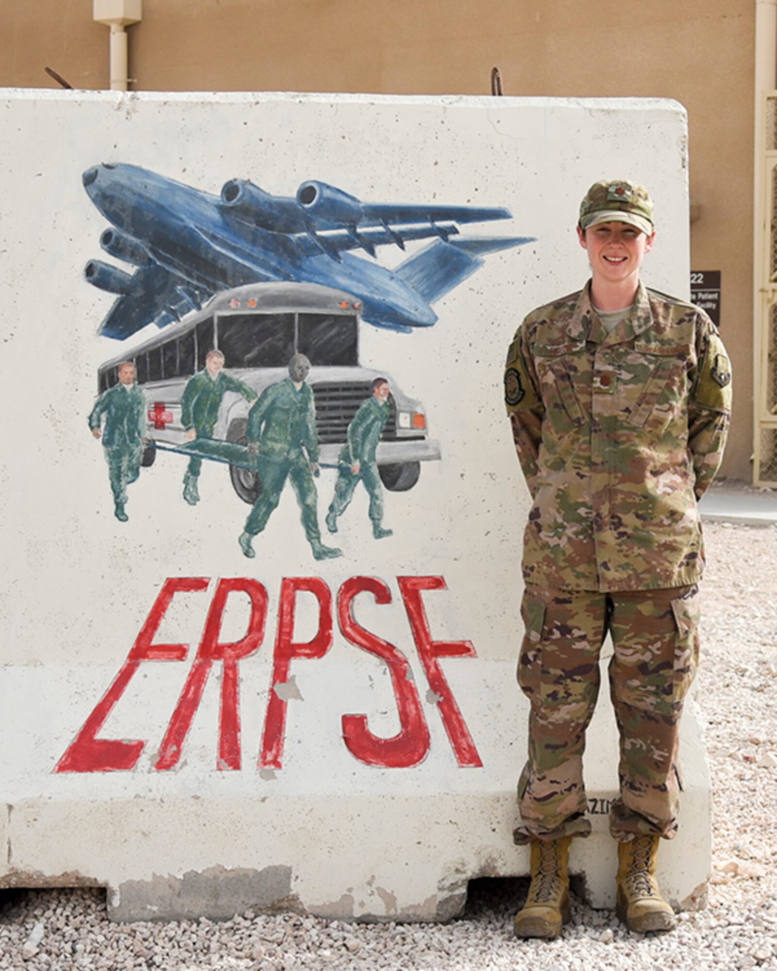 Maj. Kelly Prigge, officer in charge of the En Route Patient Staging Flight (ERPSF), stands in front of the ERPSF t-wall at Al Udeid Air Base, Qatar on May 5, 2018. The ERPSF plays a vital role in transporting patients from various deployed location and ensuring their safe and stable transport to a facility that can support the sustained injuries. (U.S. Air Force photo by Staff Sgt. Enjoli Saunders)