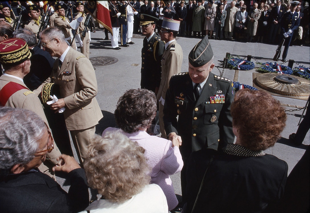 U.S. Army Gen. Crosbie Edgerton Saint, commander of U.S. Army Europe and commander of Central Army Group, shakes hands with attendees during a D-Day ceremony in an undisclosed location in June 1990.