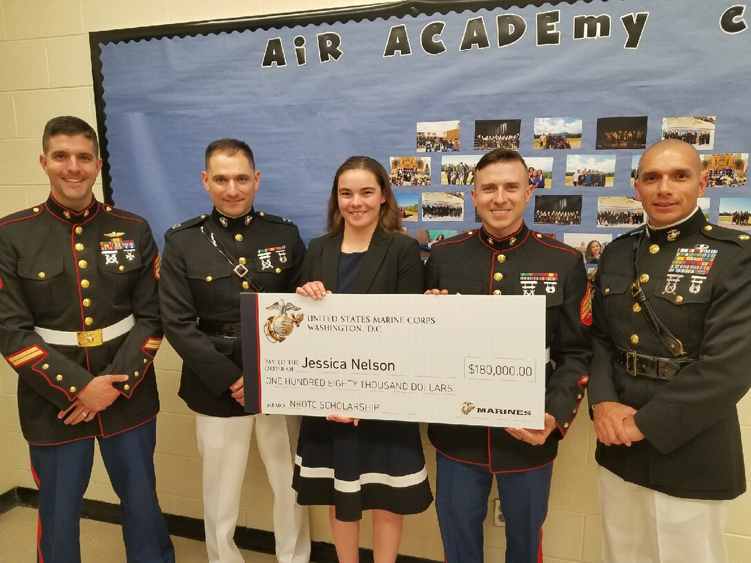 Jessica Nelson, a student at Air Academy High School, poses for a photo with Marines from Recruiting Station Denver after receiving her Naval Reserve Officers Training Corps Scholarship check during a presentation in Colorado Springs, Colorado, May 1, 2018. Eight residents of Colorado and Wyoming received the NROTC Scholarship this year.