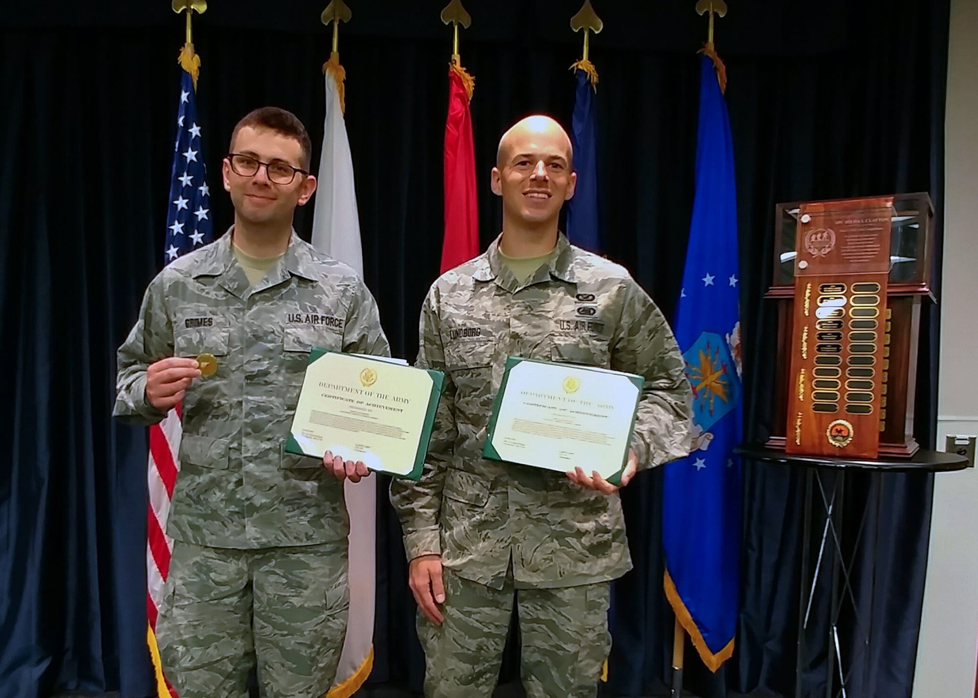 Tech. Sgt. Thomas Grimes and Staff Sgt. Corban Lundborg, both assigned to the 4th Combat Camera Squadron, display their award certificates and coins after being announced as third-place finishers of the 2018 SPC Hilda I. Clayton Best Combat Camera Competition during an award ceremony at Ft. George G. Meade, Md., May 4, 2018. The competition is an annual event open to all branches of the military, it's hosted by the 55th Signal Company (Combat Camera) in order to test the technical and tactical proficiencies of Defense Department combat photographers. (U.S. Air Force photo by Maj. Zach Anderson)