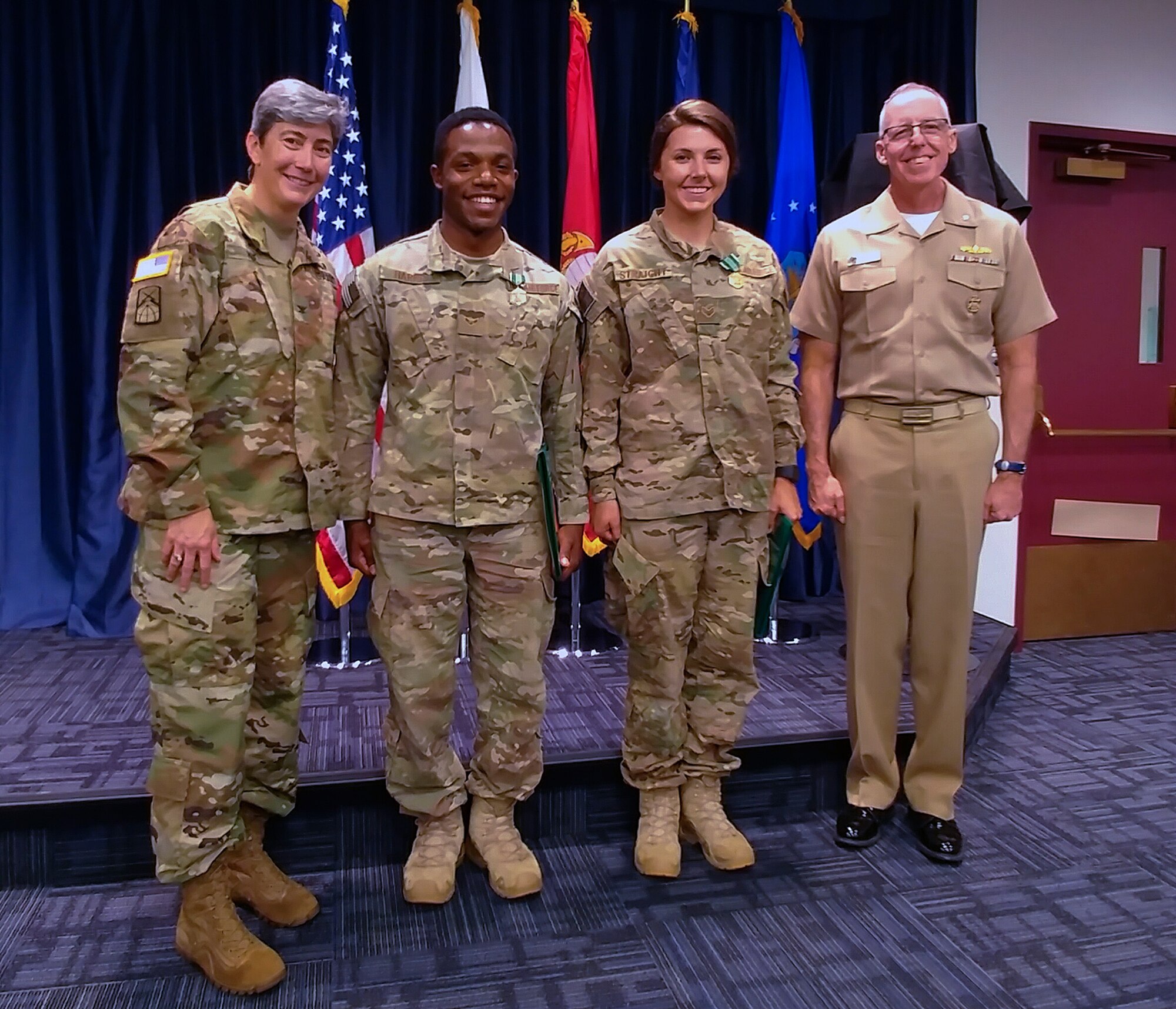 Senior Airman Maygan Straight and Airman 1st Class Franklin Harris, both assigned to 1st Combat Camera Squadron, are congratulated by Army Col. Karen J. Roe, 21st Signal Brigade commander, and Navy Cmdr. Thomas H. Cotton, Defense Media Activity Joint Combat Camera program manager, after being announced as winners of the 2018 SPC Hilda I. Clayton Best Combat Camera Competition during an award ceremony at Ft. George G. Meade, Md., May 4, 2018. The competition is an annual event open to all branches of the military, it's hosted by the 55th Signal Company (Combat Camera) in order to test the technical and tactical proficiencies of Defense Department combat photographers. (U.S. Air Force photo by Maj. Zach Anderson)