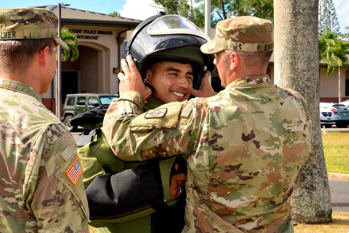 A soldier tries on a protective suit with helmet.